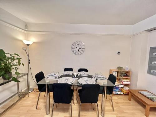 a dining room table with chairs and a clock on the wall at Glazebrook in London