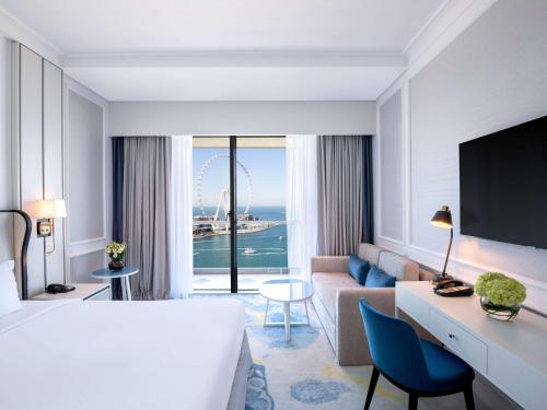 um quarto de hotel com uma cama grande e um sofá em Sofitel Dubai Jumeirah Beach em Dubai