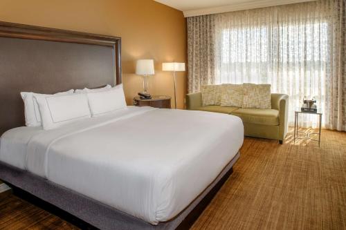 a hotel room with a large bed and a couch at Hilton St. Louis Airport in Woodson Terrace