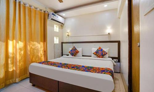 a bedroom with a large bed with orange curtains at FabExpress Prabhu Sharan in Mumbai