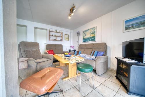 ein Wohnzimmer mit Stühlen, einem Tisch und einem TV in der Unterkunft Haus am See, App 3HAS06 in Heiligenhafen