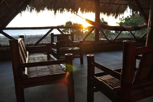 a group of chairs sitting on a beach with the sunset at Wild Waves Surf-House in Popoyo