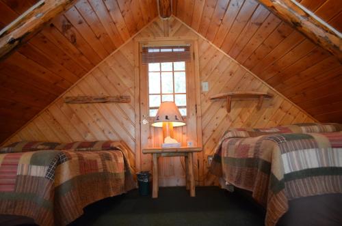 a room with two beds in a wooden cabin at Eagle Ridge Ranch in Island Park