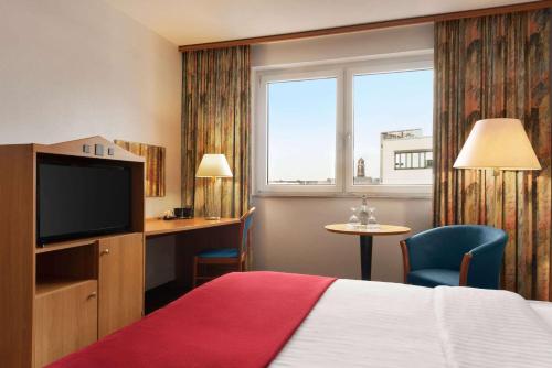 a hotel room with a bed and a flat screen tv at Ramada by Wyndham Bottrop City in Bottrop