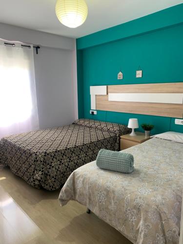 1 dormitorio con 2 camas y pared azul en Bonito Apartamento en la Macarena en Sevilla