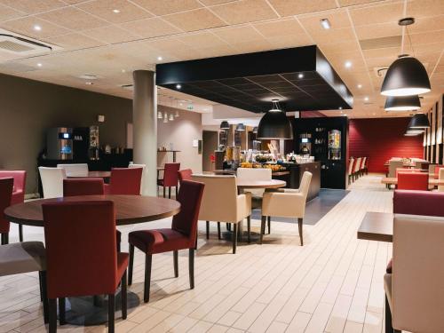 un restaurant avec des tables et des chaises ainsi qu'un bar dans l'établissement Ibis Rouen Centre Rive Gauche Mermoz, à Rouen