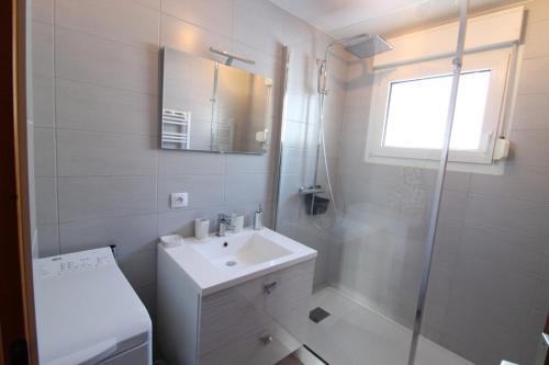 La salle de bains blanche est pourvue d'un lavabo et d'une douche. dans l'établissement Gîte Le Cosy Dream des Xettes, à Gérardmer