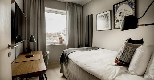 a bedroom with a bed and a desk and a window at Slottsholmen Hotell och Restaurang in Västervik