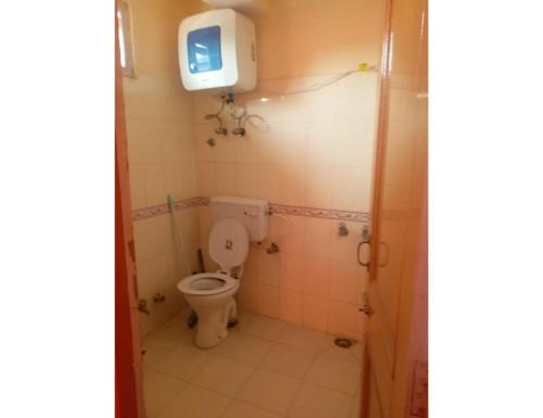 a bathroom with a toilet and a tv on the wall at Chandel Home Stay , Shimla in Shimla
