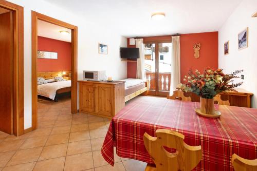 ein Wohnzimmer mit einem Tisch und ein Schlafzimmer in der Unterkunft Chalet Primula 7 in Santa Caterina Valfurva