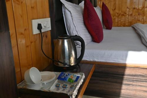 un bollitore per tè su un tavolo in una camera con un letto di Peaceful & scenic Homestay in Shoghi-Shimla a Shimla