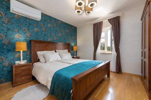 een slaapkamer met een groot bed met blauw behang bij Villa Lucija in Katun Gračanski