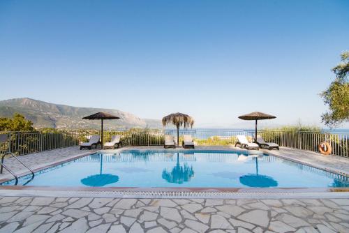 a swimming pool with chairs and umbrellas at Giorgos apartments in Dassia