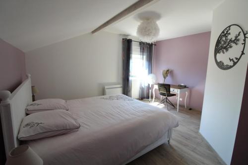 1 dormitorio con cama blanca y escritorio en Au Coin des Fées, en Les Forges