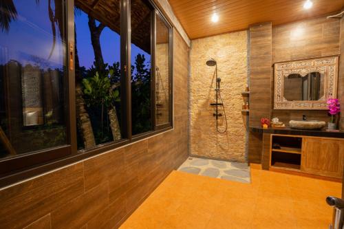 a bathroom with a shower and a sink and windows at Ubud Paras Villa in Ubud