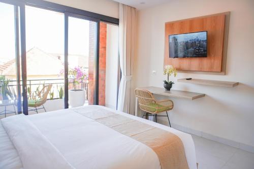 a bedroom with a white bed and a balcony at Cansa Seminyak in Seminyak
