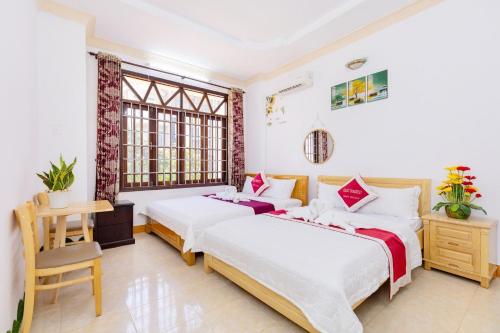 een slaapkamer met 2 bedden, een bureau en een raam bij Villages Sân Vườn ĐỨC HOÀNG in Vung Tau