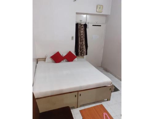 a small bedroom with a bed with red pillows at Hotel Vishal, Gaya in Gaya