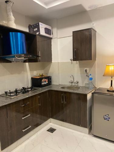 a kitchen with wooden cabinets and a sink at 1-Bed Elegant Condo at Eiffel TW in Rāmkot
