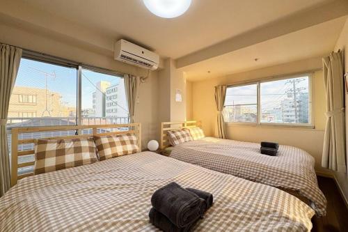 two beds in a room with two windows at Sun white Gyoutoku 301 in Tokyo
