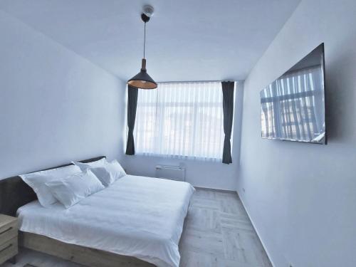 a white bedroom with a bed and two windows at Hotel Balon in Velika Kladuša