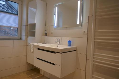 Baño blanco con lavabo y espejo en Dahmer Strand 16 Sonnenloge, en Dahme