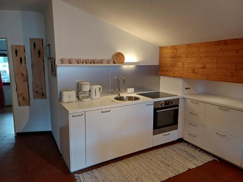 eine Küche mit weißen Schränken und einem Waschbecken in der Unterkunft Haus am Sonnweg in Maurach
