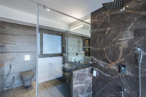 a bathroom with a glass shower and a toilet at SaffronStays Mountain Rizz in Panchgani