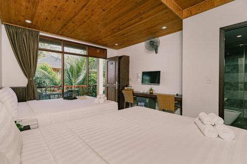 a hotel room with two beds and a television at Valentina Resort & Spa Phu Quoc in Phu Quoc