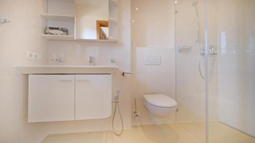 a white bathroom with a toilet and a shower at Chalet Wohnung Wilder Kaiser in Kitzbühel