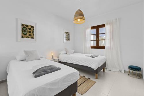 a white room with two beds and a window at Casa Estay in Playa Honda