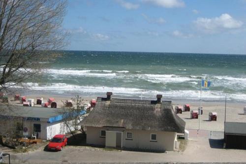 a house with a red car parked next to the beach at Strandhotel Wohnung 33 in Dahme