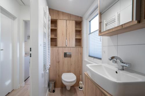 uma casa de banho com um WC branco e um lavatório. em Ostseecamp Lübecker Bucht Ferienhaus "Fuchsbau" em Scharbeutz