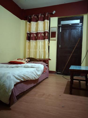a bedroom with a bed and a door and a table at GARIMA ORGANIC HOMESTAY in Bandipur