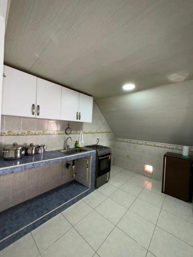 a small kitchen with white cabinets and a stove at Cabaña El Recuerdo, Paipa in Paipa
