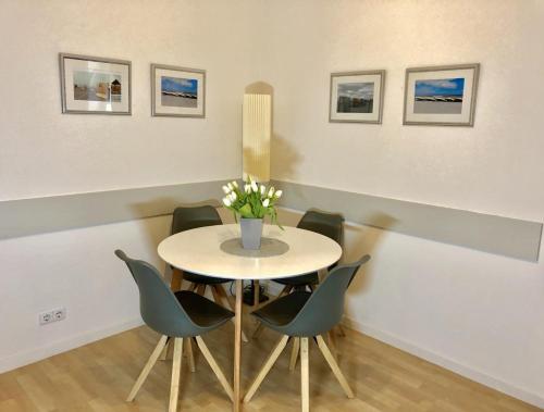 einen Tisch mit Stühlen und eine Vase mit Blumen darauf in der Unterkunft Villa Baltica Wohnung 01 in Dahme