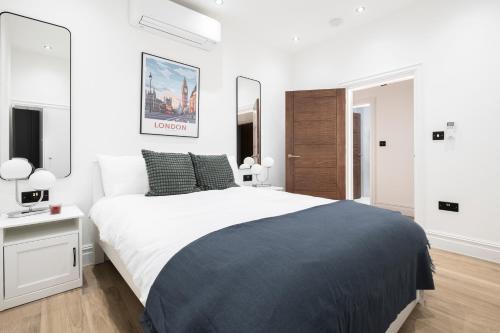 a white bedroom with a large bed and two mirrors at Luxury 2 Bedroom Apartment in Central London in London