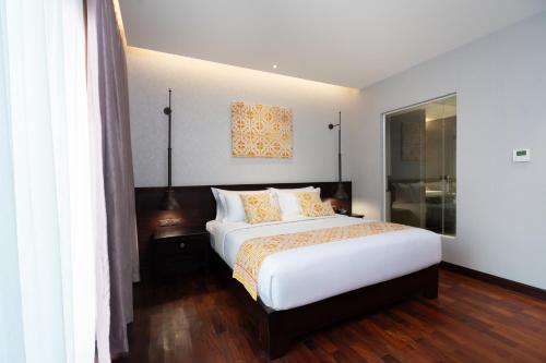 a bedroom with a large white bed and wooden floors at Mintra Hotel in Vientiane
