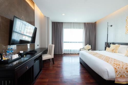 a hotel room with a bed and a desk and a television at Mintra Hotel in Vientiane