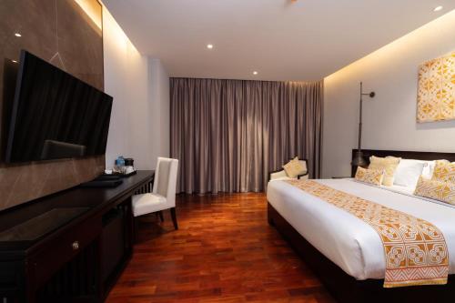a hotel room with a bed and a desk and a television at Mintra Hotel in Vientiane