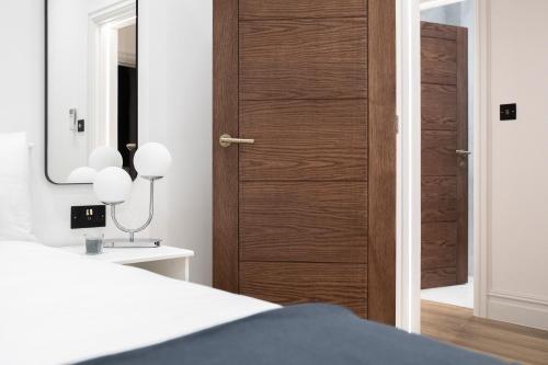 a bedroom with a wooden door with a mirror at Luxury 2 Bedroom Apartment in Central London in London