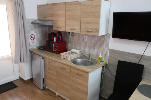 a small kitchen with a sink and a microwave at Hortobágyi Kemencés Vendégház in Hortobágy