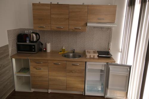 a small kitchen with wooden cabinets and a sink at Hortobágyi Kemencés Vendégház in Hortobágy