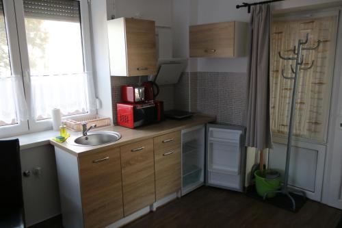 a small kitchen with a sink and a microwave at Hortobágyi Kemencés Vendégház in Hortobágy