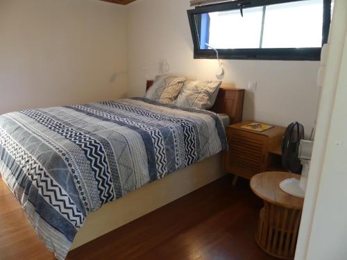 a bedroom with a bed with a blue comforter and a window at LE TUIT TUIT in Petite Île