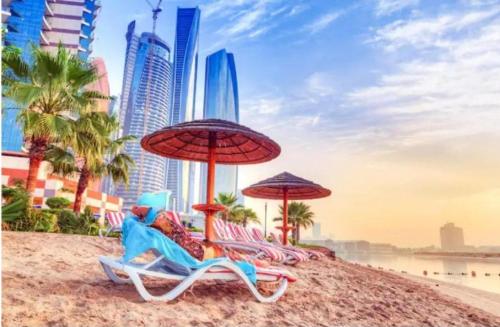 a group of beach chairs and umbrellas on a beach at Roxy Hostel in Abu Dhabi