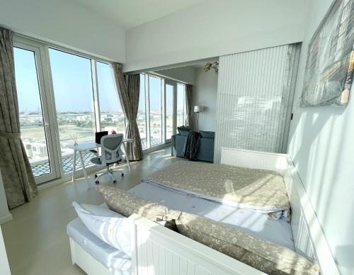 a bedroom with a bed and a desk and windows at Cozy apartment with Pool - 10 mins from Dubai Marina in Dubai