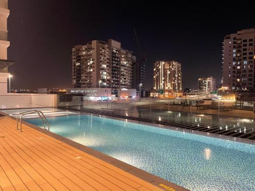 a swimming pool on the roof of a building at night at Cozy apartment with Pool - 10 mins from Dubai Marina in Dubai