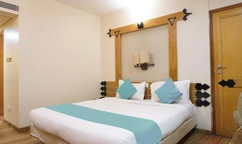 1 dormitorio con 1 cama blanca grande con almohadas azules en FabHotel Prime Deccan 8, en Pune