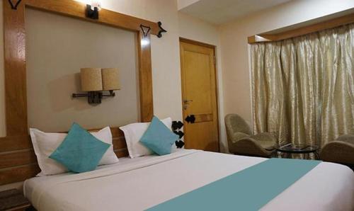 1 dormitorio con 1 cama blanca grande con almohadas azules en FabHotel Prime Deccan 8, en Pune
